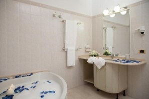 Une salle de bain équipée d’une baignoire, d’un lavabo, d’un miroir et d’un porte-serviettes.