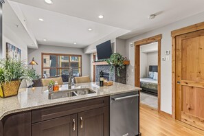 A modern kitchen with granite countertops, dark cabinetry, and a built-in dishwasher.