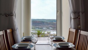 Een eettafel gedekt voor twee personen, met borden, glazen en een kleine plant.