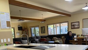 A modern kitchen with a built-in dishwasher, a dining area with a table and chairs, and a living room with a sofa and a TV. - Abel Tasman M arahau (Marahau)