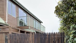 A wooden fence with a gate in front of a house with a balcony. - Abel Tasman M arahau (Marahau)