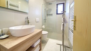 A modern bathroom with a large white sink, a glass shower enclosure, and a wooden vanity. - Apartments Loncar (Krk)