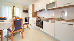 A modern kitchen with white cabinets, a wooden countertop, and a built-in oven. - Apartments Loncar (Krk)