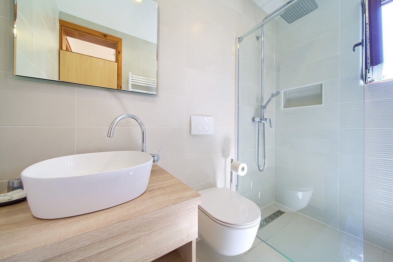 Une salle de bain moderne avec un grand lavabo blanc, des toilettes et une douche à parois de verre.