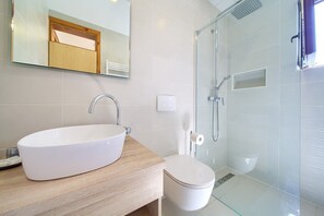 Une salle de bain moderne avec un grand lavabo blanc, des toilettes et une douche à parois de verre.