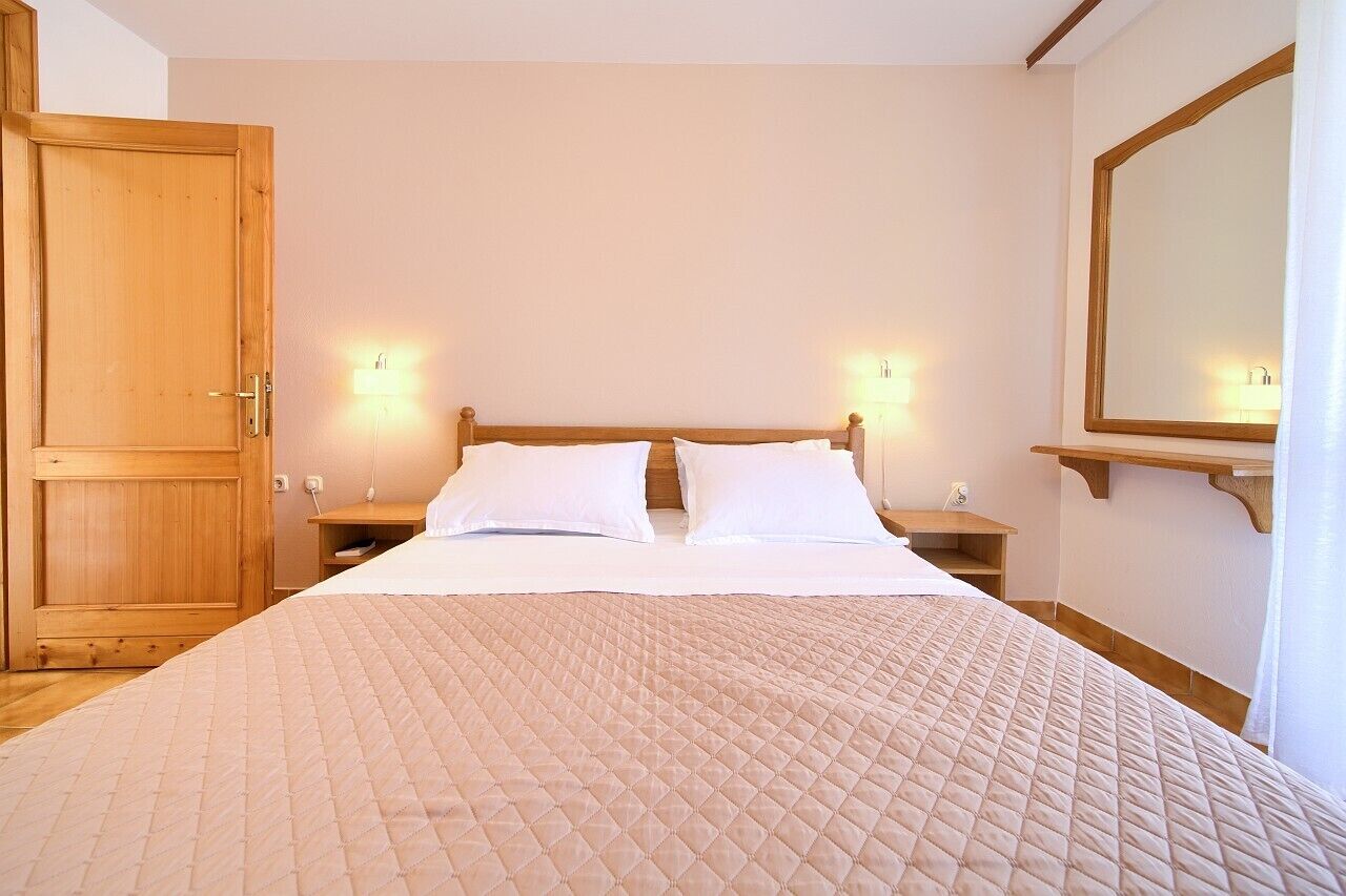 Ein Schlafzimmer mit einem großen Bett, einem Holzkopfteil, Nachttischen und einem Spiegel an der Wand.