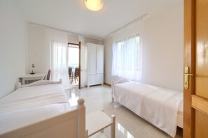 Une chambre d’hôtel avec deux lits simples, un bureau avec une chaise et une armoire.