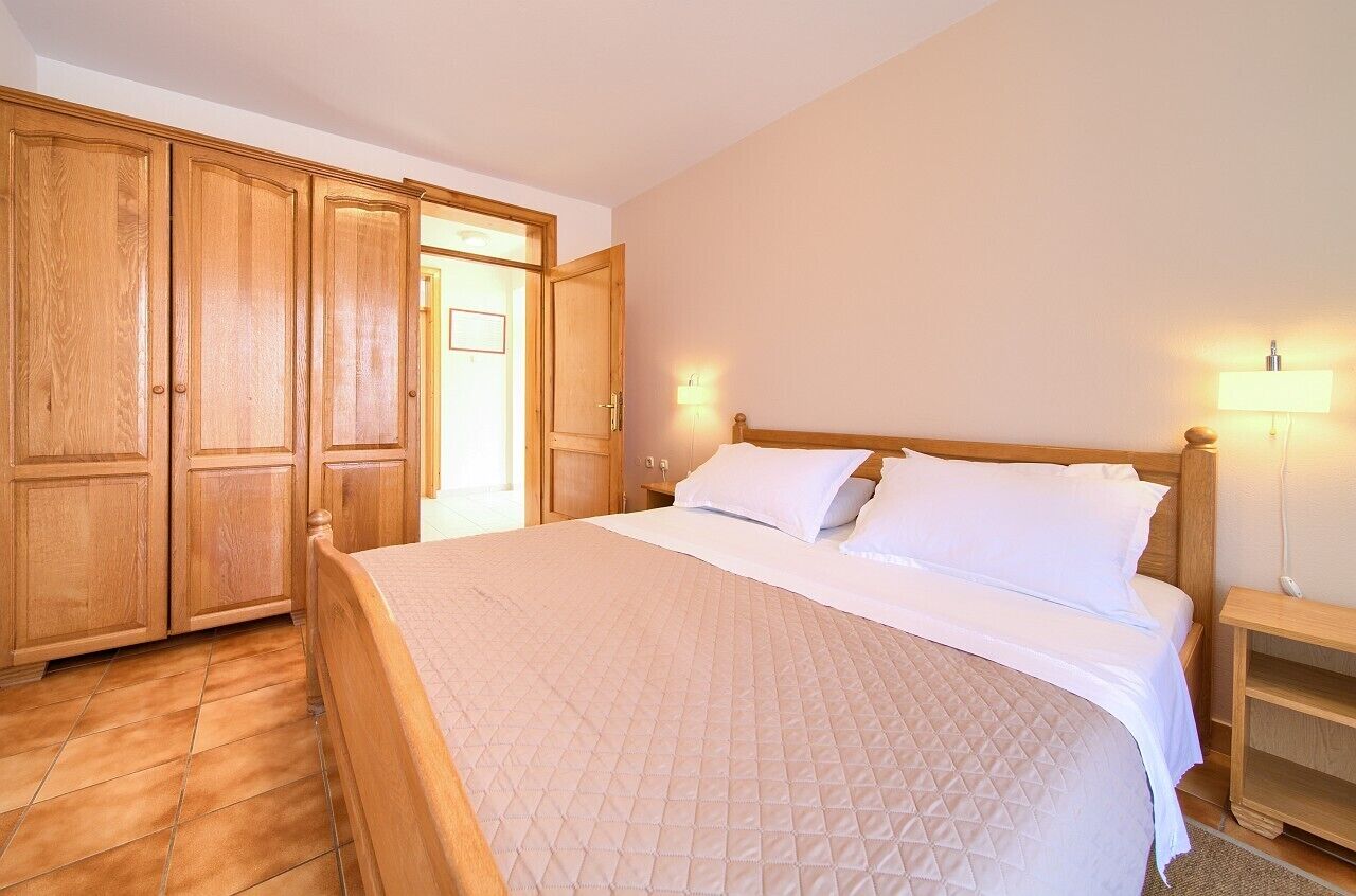 A bedroom with a wooden bed, a nightstand, and a wardrobe.