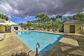 A swimming pool with lounge chairs, palm trees, and a cloudy sky. - Waikoloa Village Home in Resort Golf Community (Waikoloa Village)