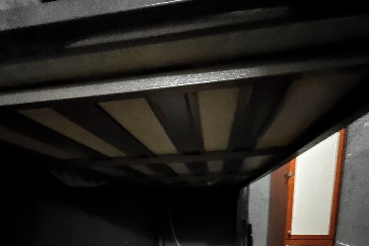 Un pasillo estrecho y tenuemente iluminado con una cama al final.