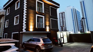 Un edificio moderno de dos pisos con fachada oscura y detalles blancos, que presenta un letrero con la leyenda 'Zircon Hotel'.
