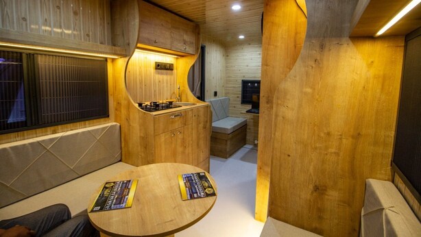 Un interior compacto y moderno con paredes de madera y una zona de cocina integrada.