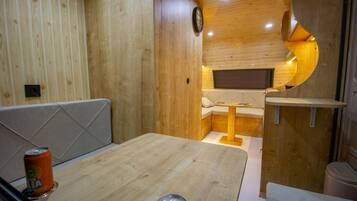 A compact, wooden interior with a dining area, a small seating nook, and a built-in TV.