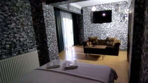 Una habitación de hotel con cama, sofá, televisión de pantalla plana y una mesa con lámpara.