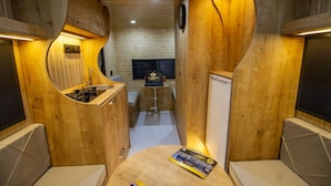 Un interior acogedor de madera con kitchenette, zona de estar y una pequeña mesa con una revista.
