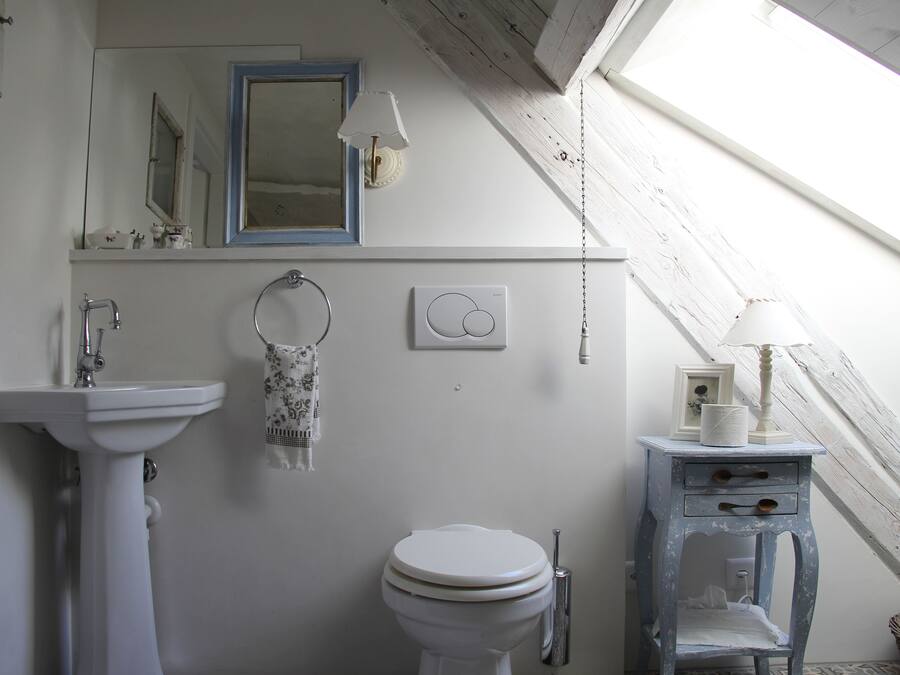 Casa de banho com lavatório branco, sanita e cómoda azul com gavetas.