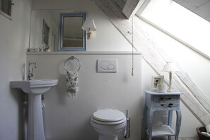 Un baño con lavamanos blanco, inodoro y tocador azul con cajones.