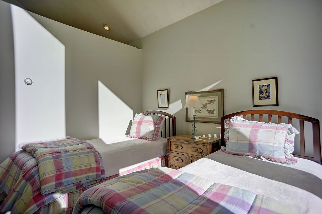 A bedroom with two beds, a nightstand, and a lamp.