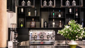 A bar area with shelves of liquor bottles, a coffee machine, and a decorative plant. - Hotel Varese Roma (Rome)