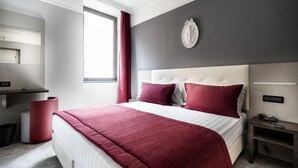 A modern hotel room with a large bed, a desk with a telephone, and a wall-mounted clock. - Hotel Varese Roma (Rome)