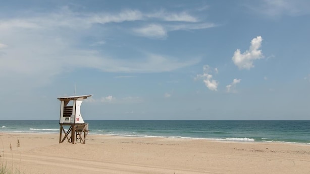 A lifeguard tower on a beach with a clear sky.