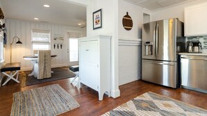 A modern kitchen with white cabinetry, stainless steel appliances, and a wooden floor.