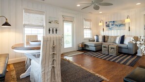 A living room with a dining table, sofa, and a ceiling fan.