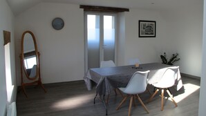 Spiseområde med et bord, stole, en træstol, et ur, et indrammet billede og en skydedør.