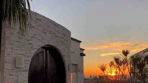 Un bâtiment doté d’une grande entrée en arc de cercle, d’un chemin pavé et offrant une vue sur le coucher du soleil.
