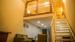 A multi-level living space with a staircase, a green sofa, and a small table. - The CEO Executive Office Suites (George Town)