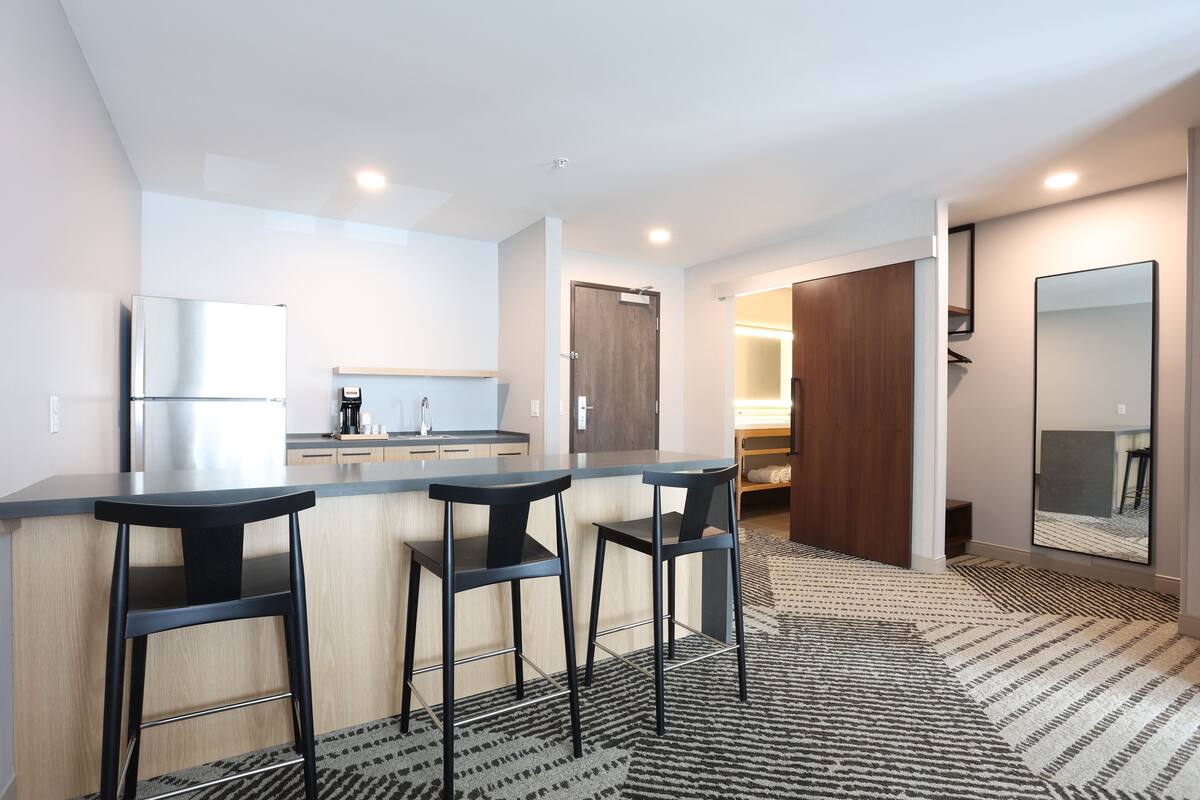 A modern kitchen with a bar area, a refrigerator, and a coffee maker.