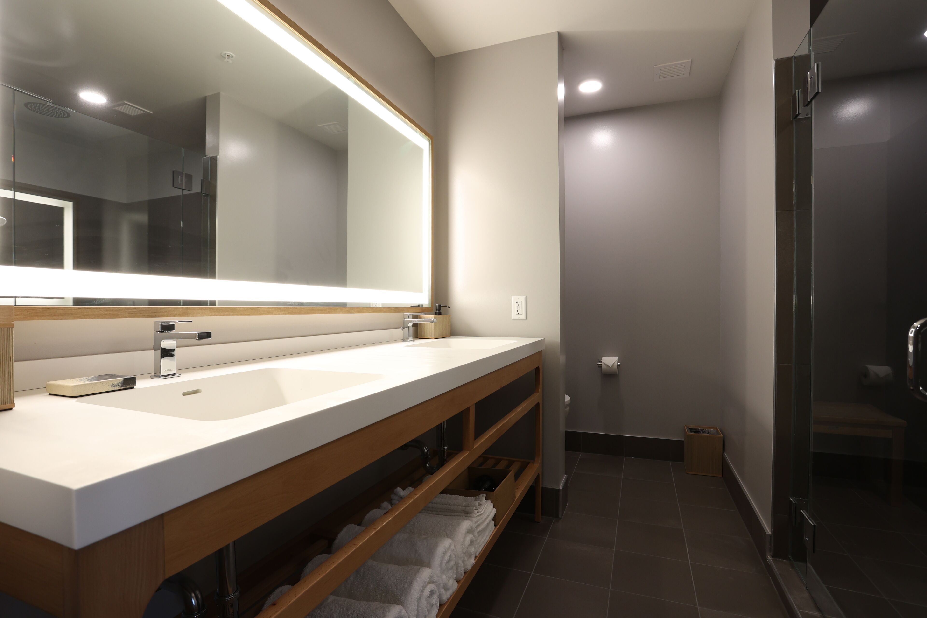 A modern bathroom with a double sink, a large mirror, and a glass shower enclosure.