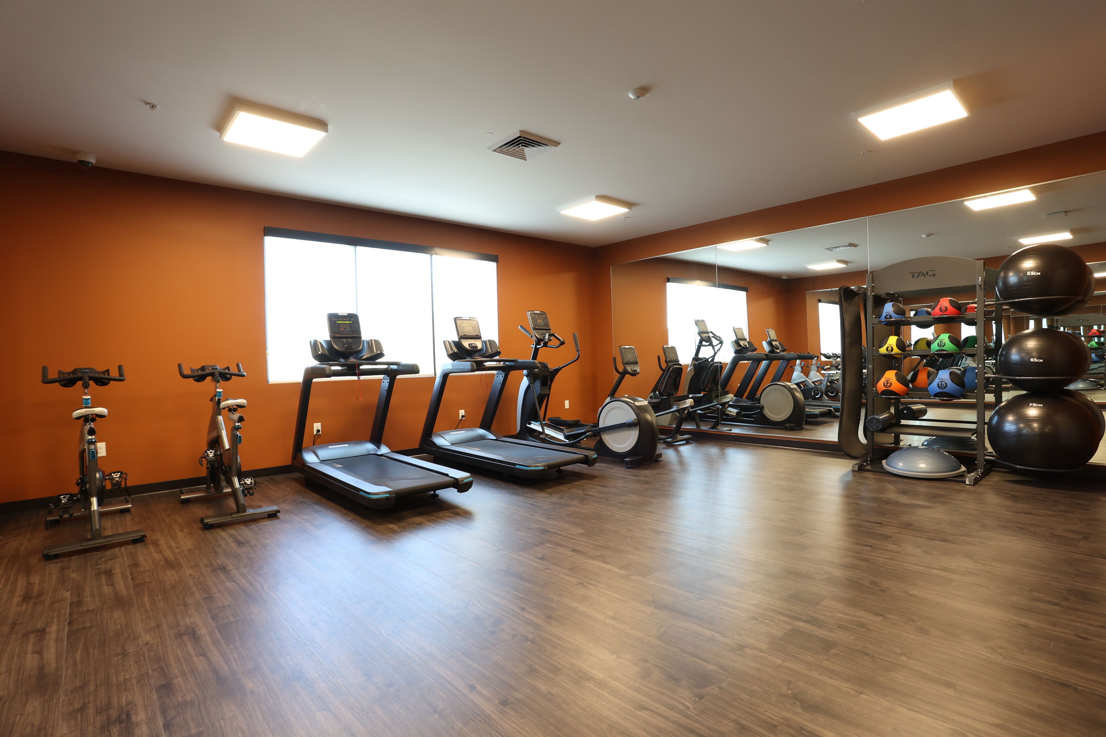 A gym with treadmills, elliptical machines, and a weight station.