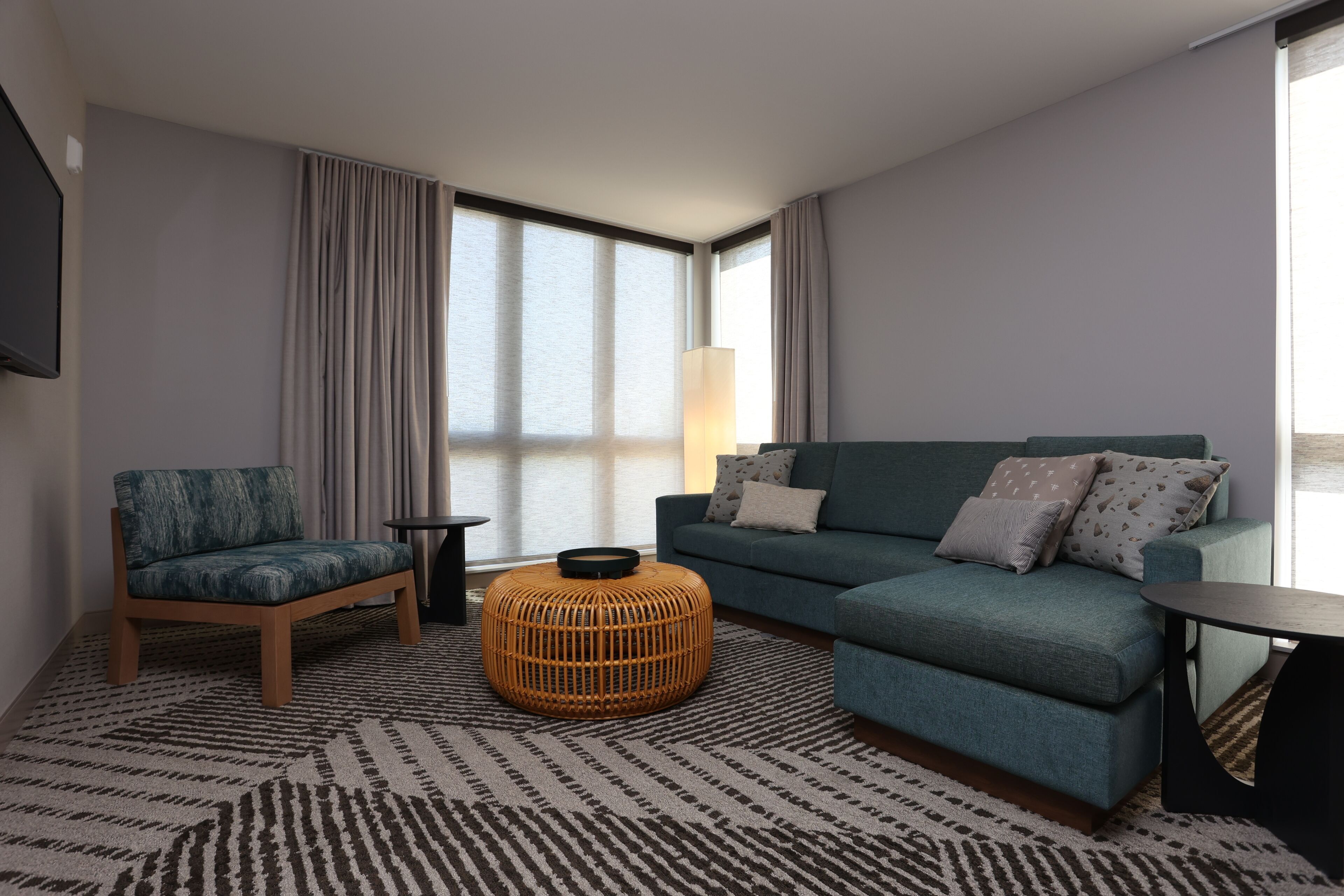 A modern living room with a sofa, armchair, and a round ottoman.