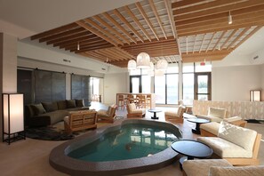 A spacious living area with a pool, wooden ceiling beams, and modern furniture. - Cedartree Hotel Portland Hillsboro (Hillsboro)
