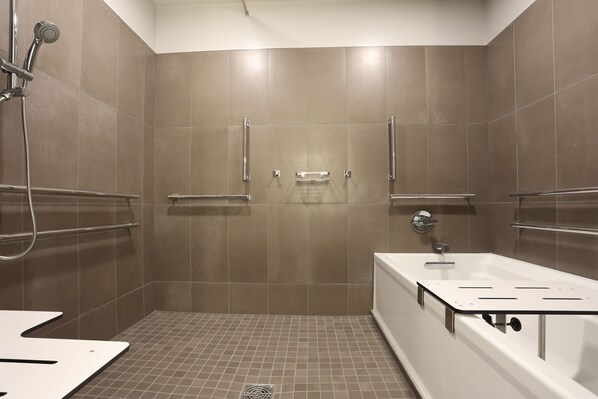 Un baño moderno con ducha a nivel, barras de apoyo y bañera.