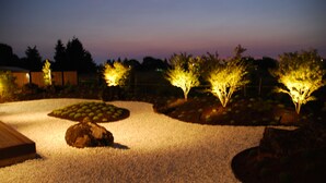 A landscaped garden with illuminated trees and a gravel path. - Cedartree Hotel Portland Hillsboro (Hillsboro)