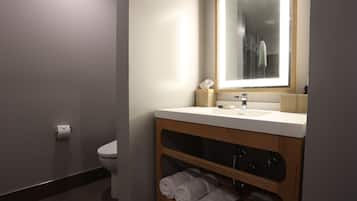 A modern bathroom with a toilet, a sink with a mirror, and a towel rack.