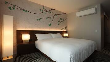 Quarto de hotel com uma cama grande, duas luminárias de cabeceira, ar condicionado fixado na parede e um tapete estampado.