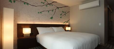 Une chambre d’hôtel avec un grand lit, deux lampes de chevet, un climatiseur fixé au mur et un tapis à motifs.