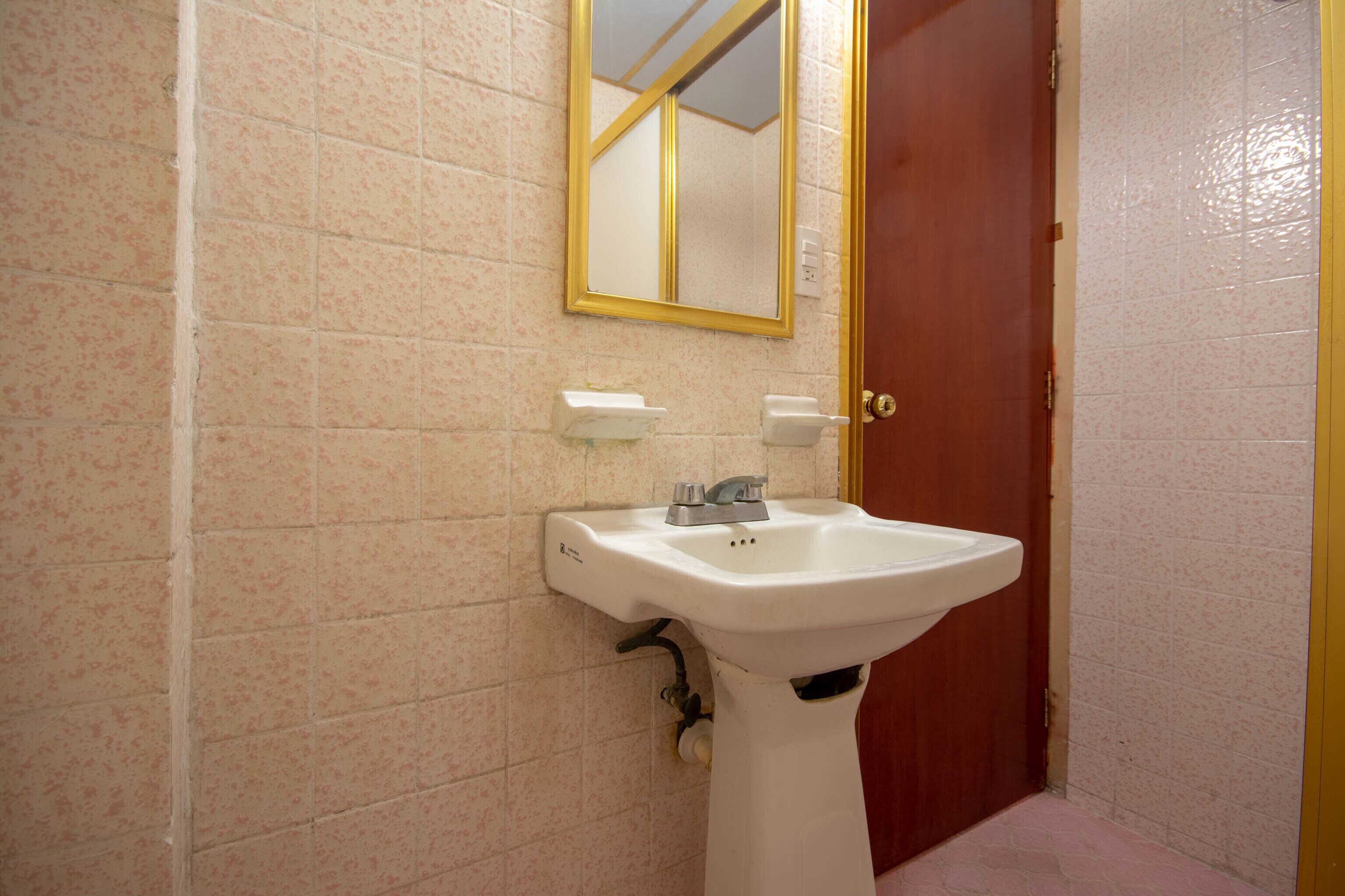A bathroom with a white sink, a mirror, and a red door.