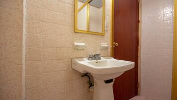 A bathroom with a white sink, a mirror, and a red door.