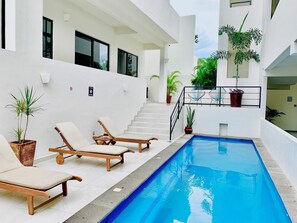 A modern pool area with lounge chairs and a staircase leading to an upper level. - Saltwater Pool + Rooftop Terrace-Walk to Beach (Sayulita)