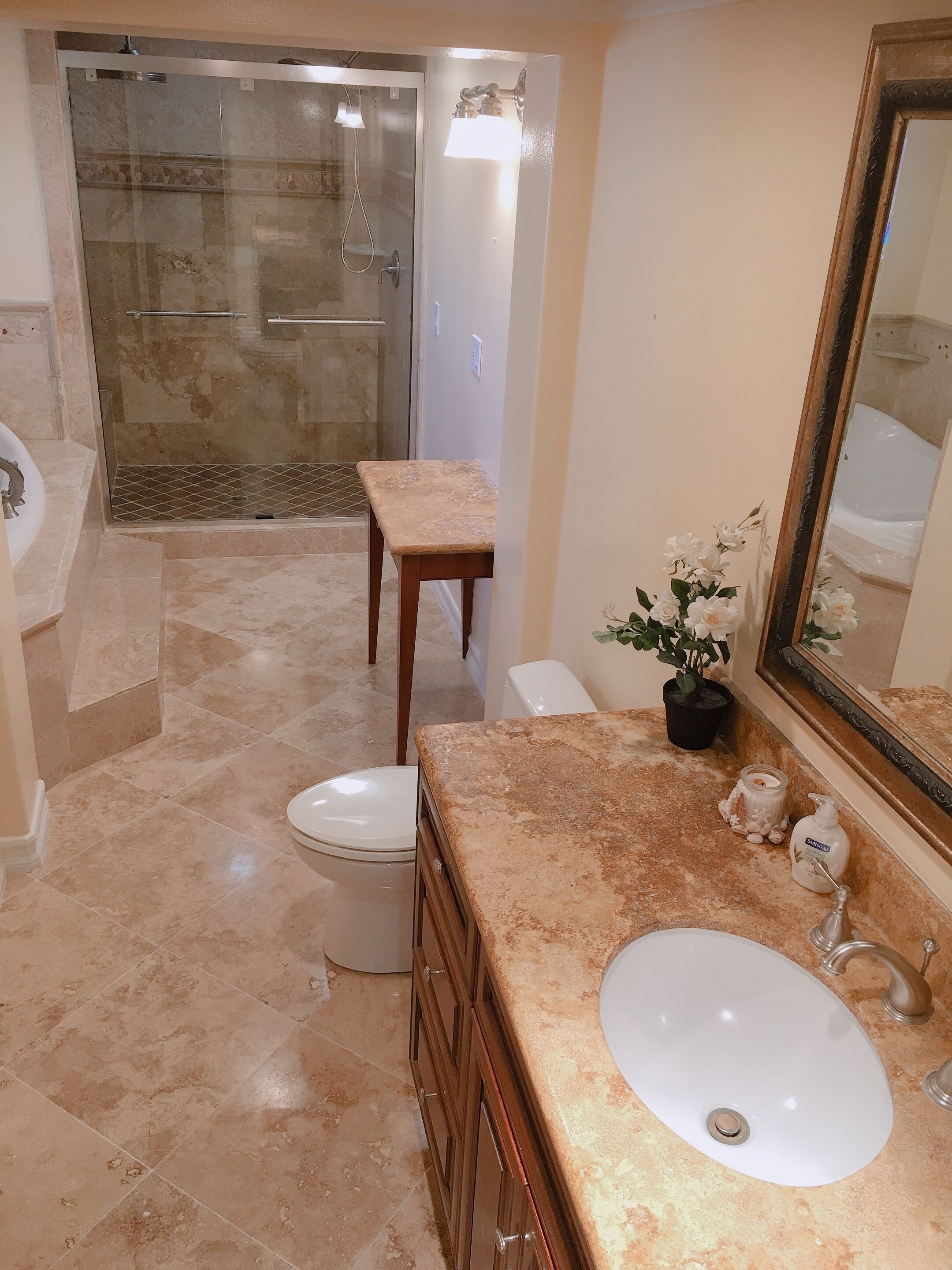 A bathroom with a shower, toilet, sink, and a mirror.