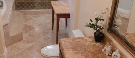 A bathroom with a shower, toilet, sink, and a mirror.