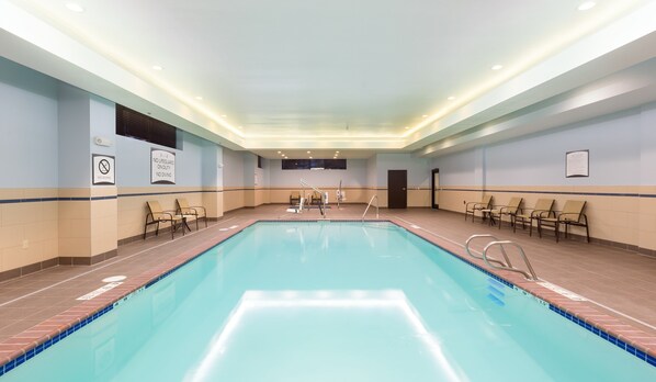 A large indoor swimming pool with clear water, surrounded by lounge chairs and a no diving sign on the wall.