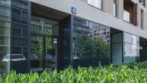 A modern building with a glass entrance, a sign indicating the address, and a view of the surrounding area. - P&O Kolejowa 3 (Warsaw)