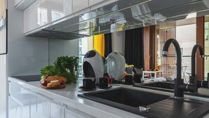 A modern kitchen with a black countertop, stainless steel appliances, and a large window offering a view of the outdoors. - P&O Kolejowa 3 (Warsaw)
