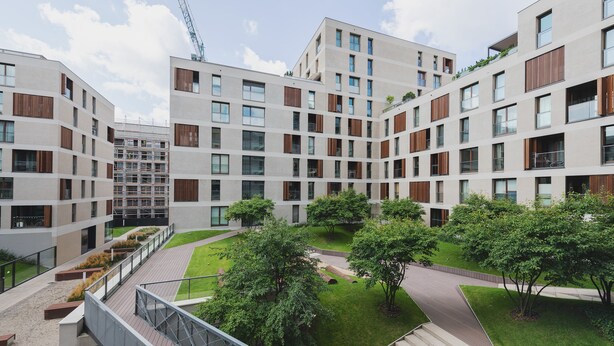 A modern apartment complex with multiple floors, balconies, and a central courtyard with trees and pathways. - P&O Kolejowa 3 (Warsaw)