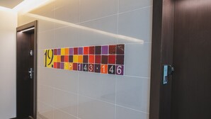 A hallway with numbered tiles on the wall, a door, and a wall-mounted sign. - P&O Kolejowa 3 (Warsaw)